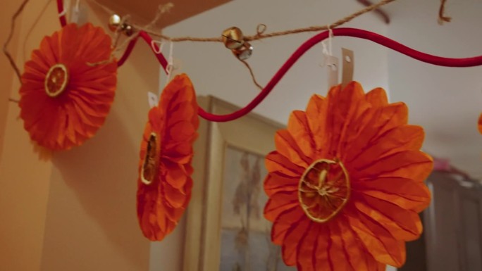 一串节日装饰品:铃铛，纸花，干橙子。