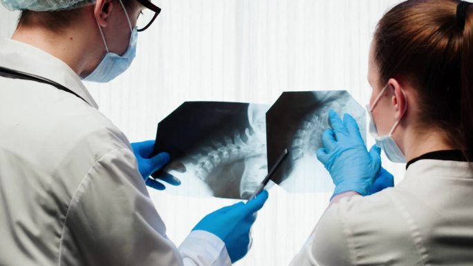 医生检查颈部x光特写。脊柱、头颅的磁共振成像。男女治疗师在看脊柱骨骼的x光片。医疗保健和医药概念。