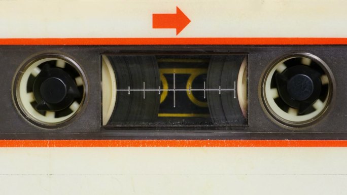 微距静态相机视图的老式音频盒式磁带与白色标签在使用播放盒式磁带机。所有的殴打，灰尘和褪色的标签颜色。