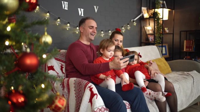 圣诞节期间一家人带着三个小女儿用手机看有趣的视频