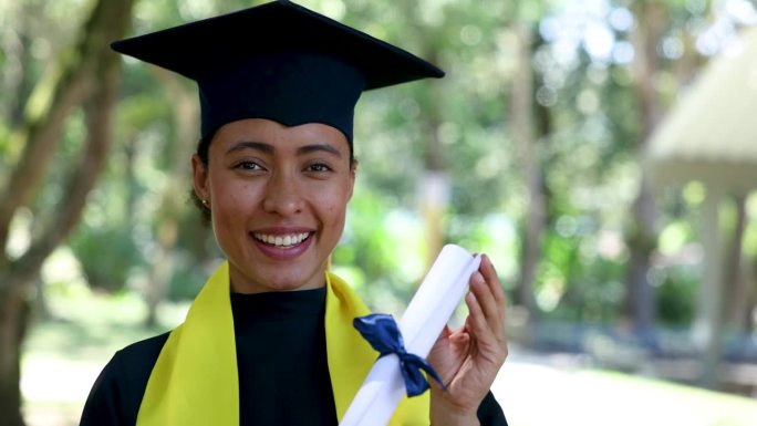 一个快乐的非洲裔美国女学生，毕业后拿着毕业证书面对镜头微笑