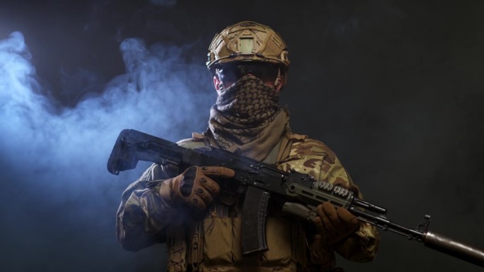 一个勇敢的士兵，身穿防护战服，手持机关枪站在黑暗的背景上，笼罩在烟雾中。战争和军事概念。