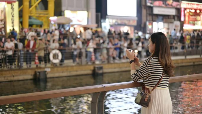 亚洲z世代独自旅行在日本大阪道顿堀自拍并分享她的社交媒体