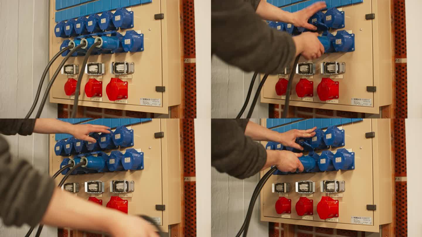 电气面板与蓝色16A和红色32A三相连接器和配电箱。技术人员从相邻的插座上拔下三根电缆。