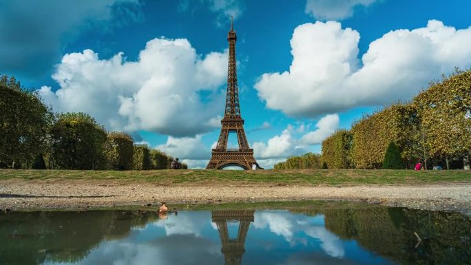 在法国巴黎的夏季，游客在战神广场公园散步，可以看到埃菲尔铁塔