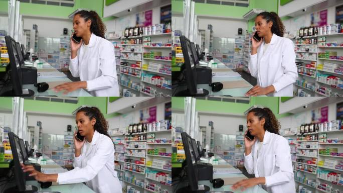 黑人女药剂师一边在药店打电话接外卖单，一边在电脑上查看是否有货
