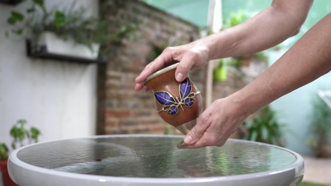 双手轻轻摇动一个马黛茶葫芦，展示了搅拌马黛茶叶子以增强马黛茶浸泡的过程。