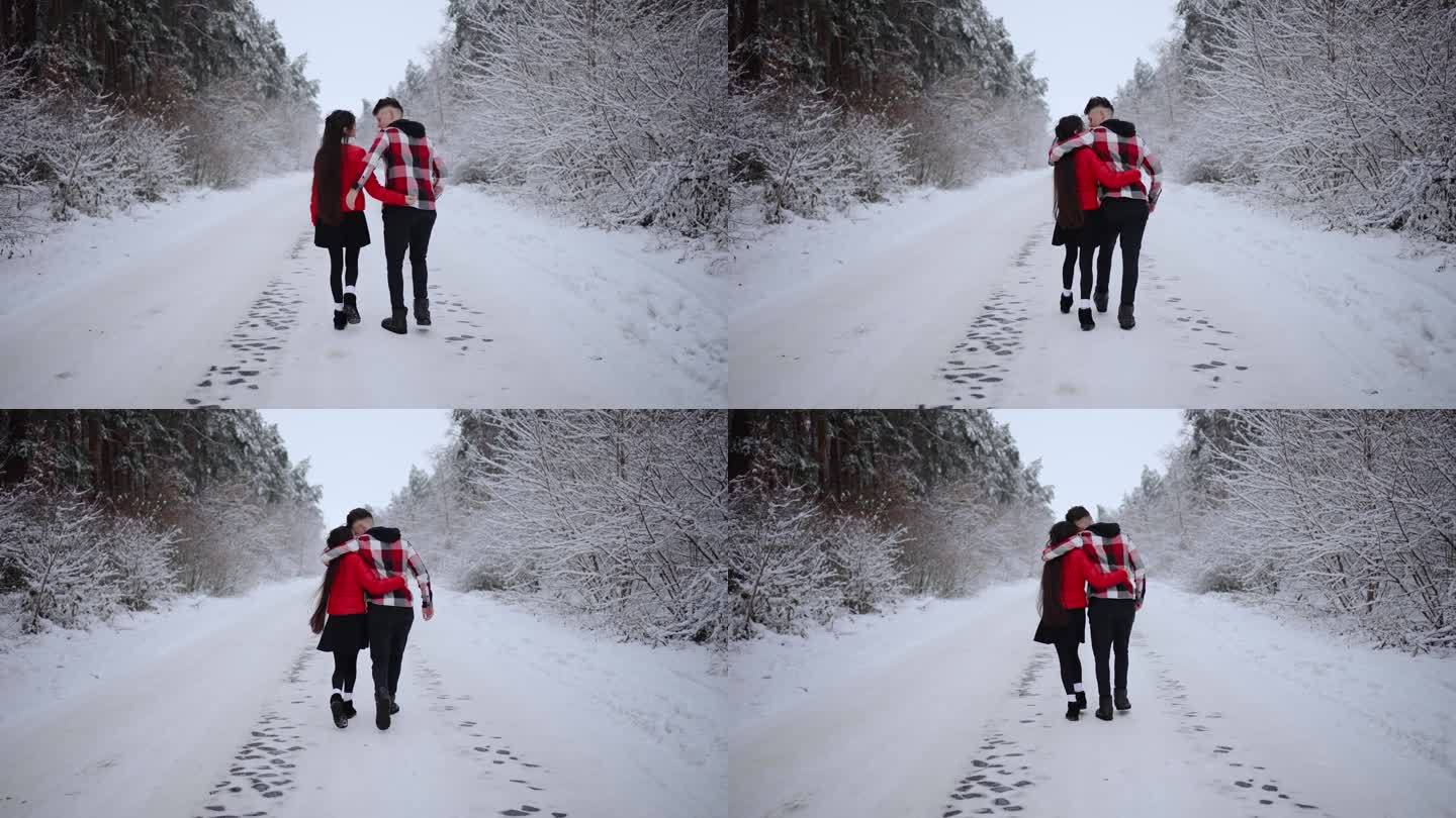 一对相爱的情侣拥抱着走过一片白雪皑皑的森林