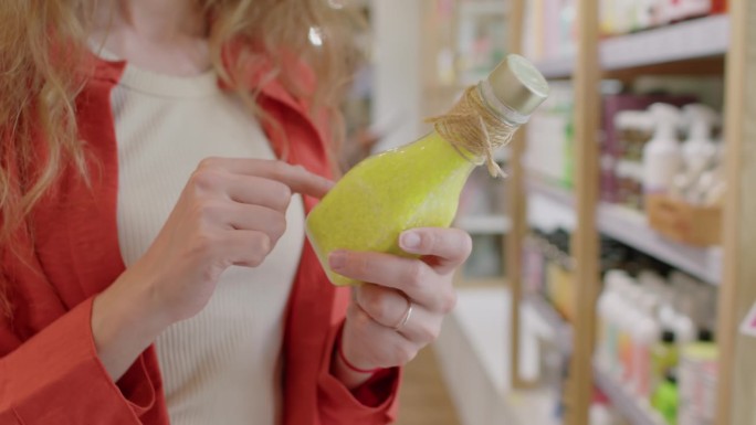无法辨认的女人阅读黄色瓶子里的发膜成分