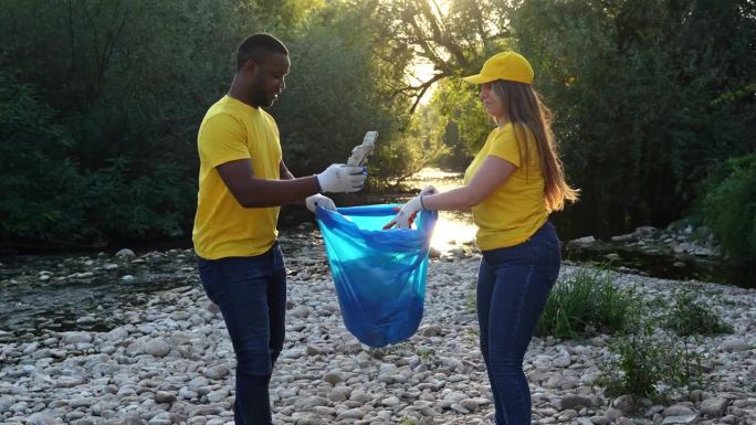 男志愿者和女志愿者在清理完河岸上的垃圾后握手