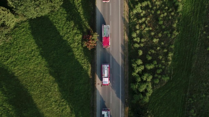 鸟瞰消防车车队在日落迷人的绿色风景4k
