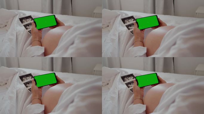 孕妇手持绿色色度键屏的智能手机。
