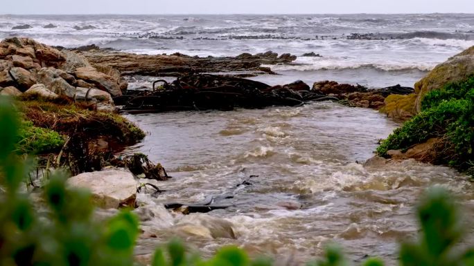 浑浊的雨水从排水系统进入海岸线上的海洋