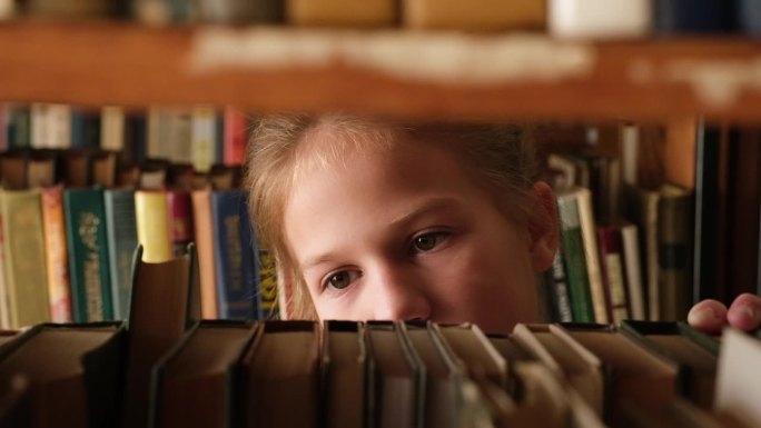 小女孩在旧图书馆的书架上挑书。选文学读物的女学生