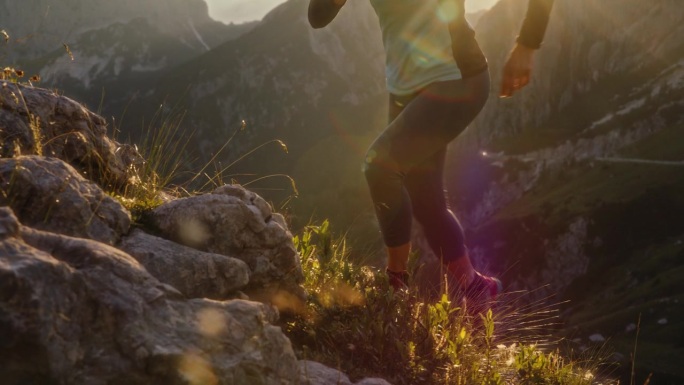 SLO MO女徒步旅行者穿着运动服在阳光灿烂的芒加特山上跑步