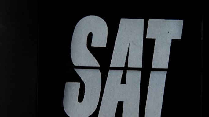 黑色翻盖时钟上的日表特写，上面用白色粗体字写着“SAT”，象征着周末时间的跟踪。