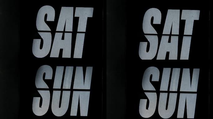 黑色翻盖时钟上的日表特写，上面用白色粗体字写着“SAT”，象征着周末时间的跟踪。