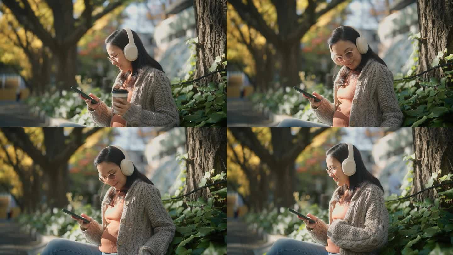 放松的孕妇坐在公园里，在树下休息。在假期听音乐