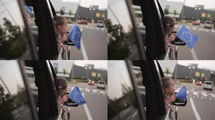 车窗边快乐的女孩手里拿着欧盟的旗帜。慢动作