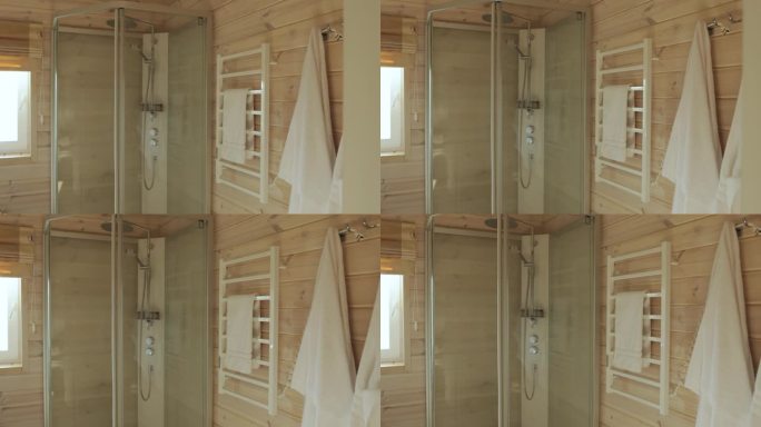 淋浴间，一个加热毛巾架，毛巾和白色毛巾挂在木墙的钩子上，在空荡荡的小浴室里慢动作。