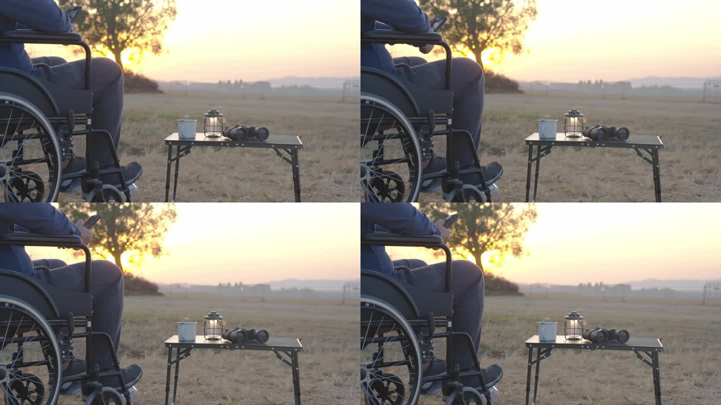 一个人坐在轮椅上，看着第一个金色的日出。残疾人有希望。
