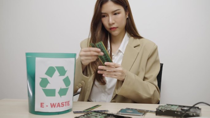 电子废物管理。一位美丽的亚洲女子将电子垃圾放入塑料箱，以便回收或妥善处理。环境可持续性。电子垃圾。