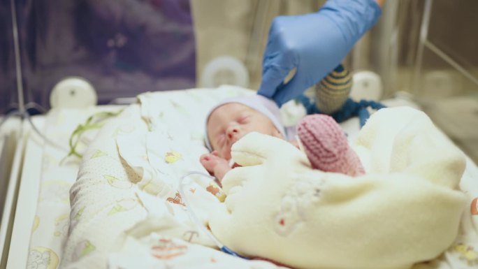 医院新生儿重症监护室，不认识的医生用听诊器检查早产儿。新生儿放在保温箱中。