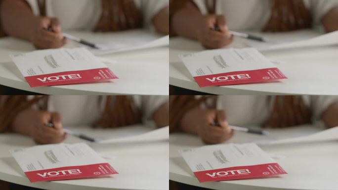 一个“投票!”信封的静态锁定镜头，一名黑人妇女在家中查看邮寄的总统、参议院、国会或地方选举投票选票