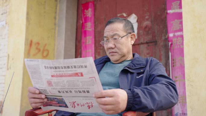 老人坐在门前喝茶听京剧看报纸