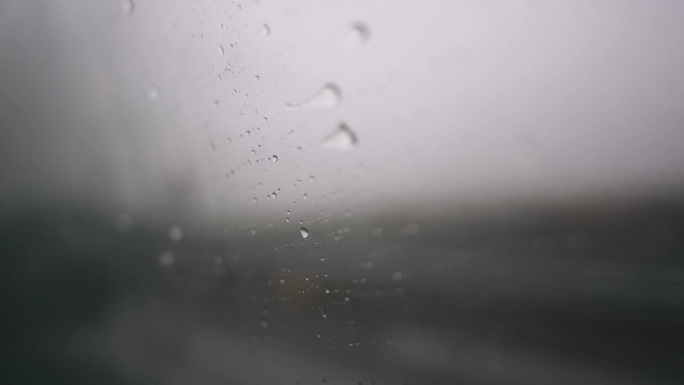 雨滴落在驾驶汽车的侧窗玻璃上。在雨中开车