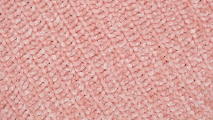 柔软的针织羊毛详细的纹理。天然织物近距离针织图案。粉红色针织品，温暖的羊绒表面。旋转,宏。舒适的纺织