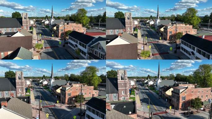 明媚秋日里的美国小镇。主干道上悬挂美国国旗的房屋和教堂的航拍照片。