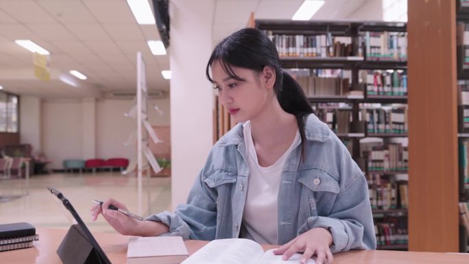 一名亚洲女学生在大学图书馆的平板电脑上高兴地查看自己的考试成绩。她的得意流露出考试的圆满结果，给图书
