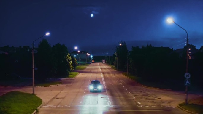 夜晚，月亮在天空中，夏天，汽车驶过城市街道上的减速带。无人驾驶飞机。