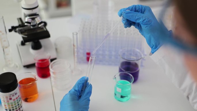 实验室科学家用移液管分析一种清澈的液体，将DNA和分子提取到试管中