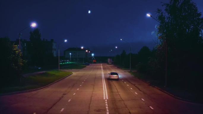 夜深人静的郊区街道上，一辆孤独的汽车驶过。无人驾驶飞机。