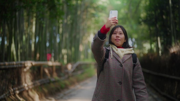 一位女游客在京都岚山竹林使用她的智能手机