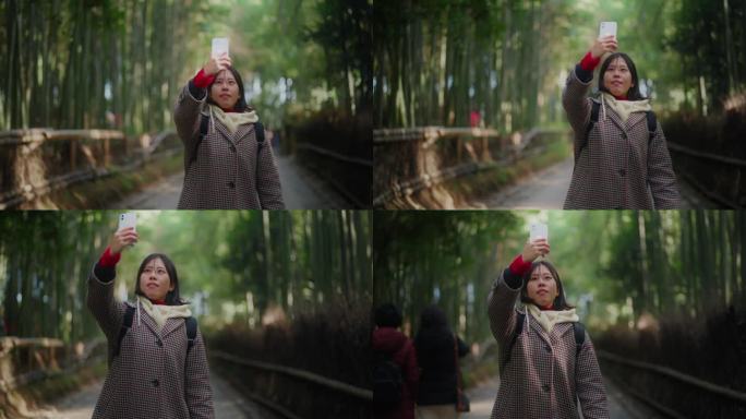 一位女游客在京都岚山竹林使用她的智能手机