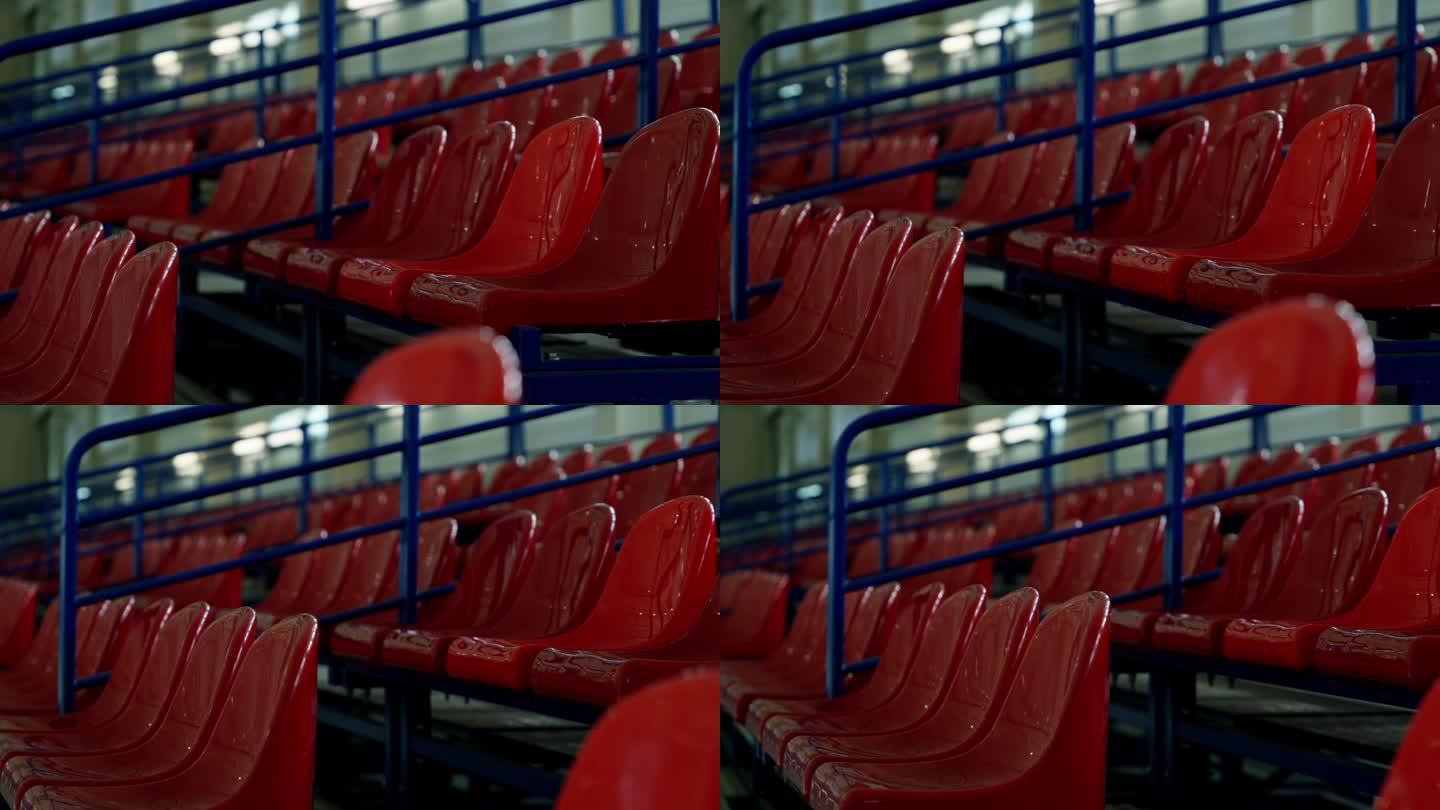 室内体育馆里的一排椅子。红色的席位。将相机从右向左移动。