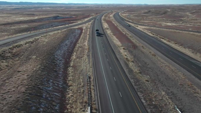 无人机拍摄的半卡车与平板拖车装载物资在一个阳光明媚的冬日双车道州际公路