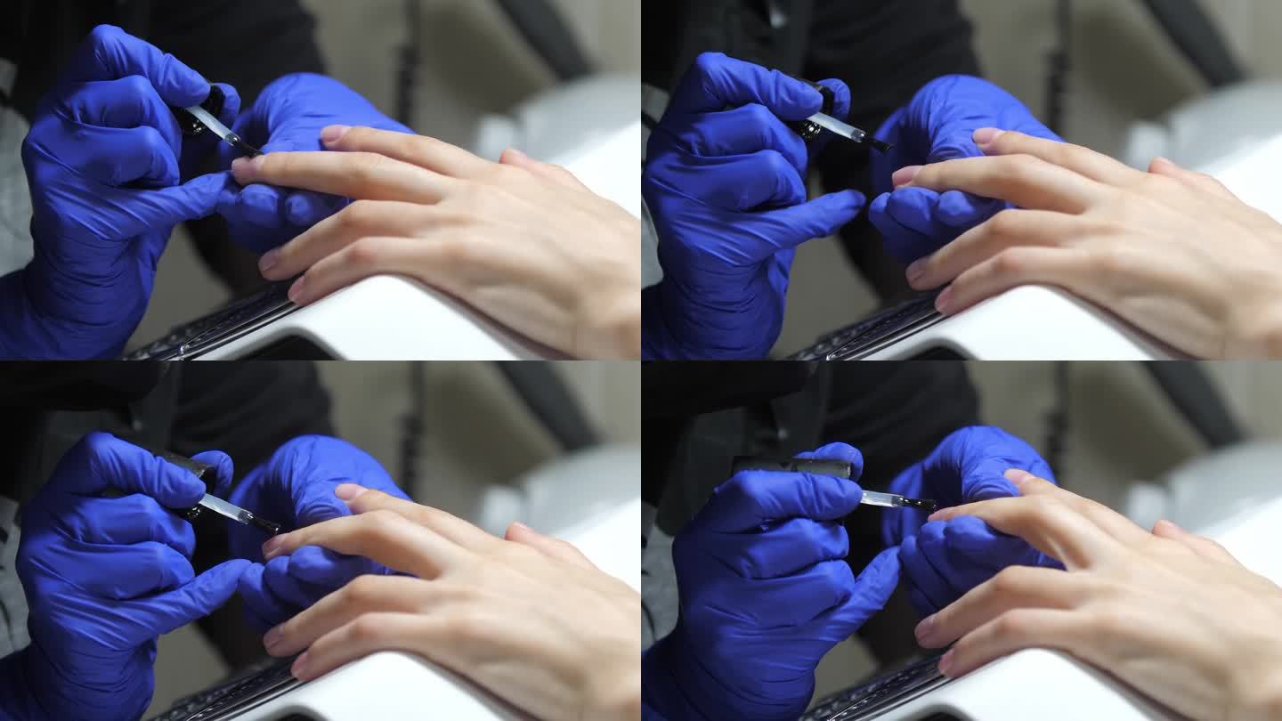 美甲沙龙的美甲服务。在美容院，戴着蓝色手套的专业美甲师正在涂透明凝胶指甲油。修剪整齐的指甲。概念美甲