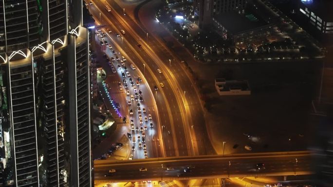 多层照明道路从夜间鸟瞰迪拜哈利法塔在阿联酋。高速公路岔路口交叉口。高速公路上车辆的俯视图。建筑结构。