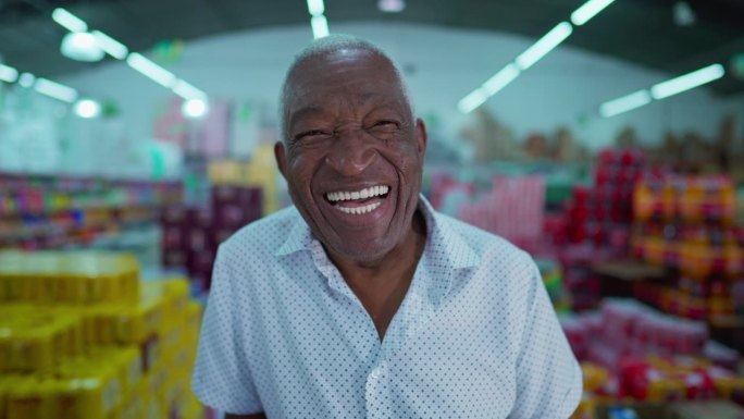 一位快乐的巴西黑人老人微笑着站在杂货棚里，身后是消费品