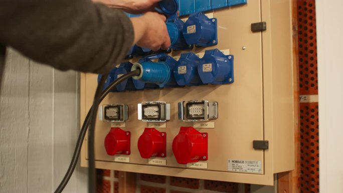 电气面板与蓝色16A和红色32A三相连接器和配电箱。技术人员拔掉不同排插座上的两根16A电缆。