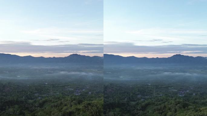 在印度尼西亚戈龙塔洛山脉的清晨日出时飞越云层。金色蓬松的云轻轻地划过天空，阳光洒下美丽的光芒