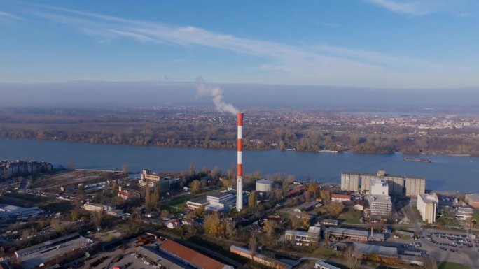 航拍画面上升并聚焦在塞尔维亚城市贝尔格莱德的一个烟囱上，背景是多瑙河。
