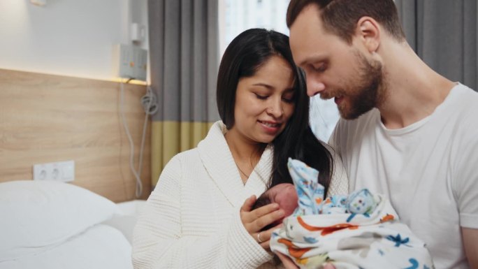 一对幸福的父母带着刚出生的儿子在产后医院的托儿所。墨西哥多民族新生儿，母亲和父亲在产后医院。母性和亲