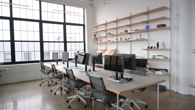 在现代办公室里，桌子周围是电脑和椅子