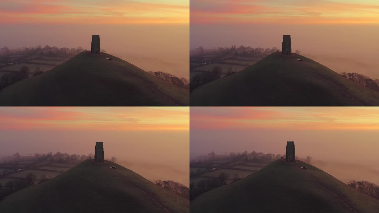 英国萨默塞特郡，朦胧的格拉斯顿伯里山日出鸟瞰图，色彩斑斓的天空与背景中的乡村