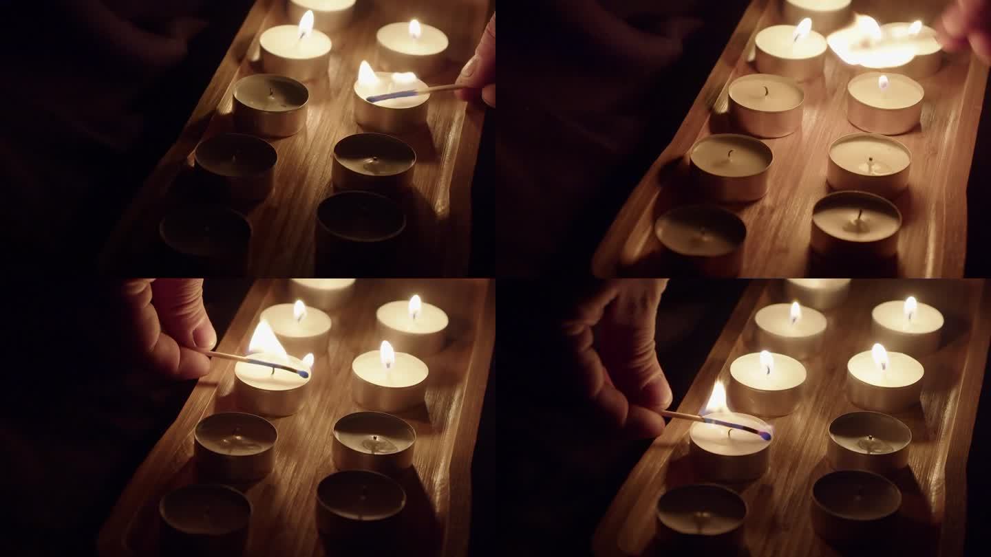 男子在黑暗的画室里点上茶烛，火焰在木托盘里闪烁